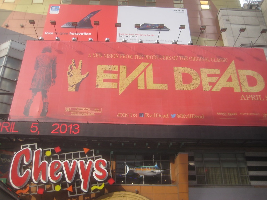 En stor reklamskylt för skräckfilmen 'Evil Dead' från 2013 på en byggnadsfasad.