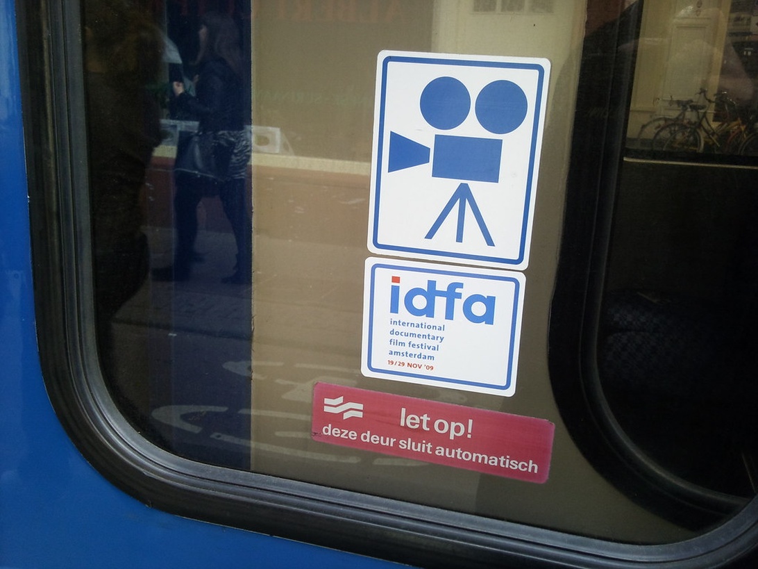 Närbild på klistermärken för filmfestivalen IDFA med dess logotyp.